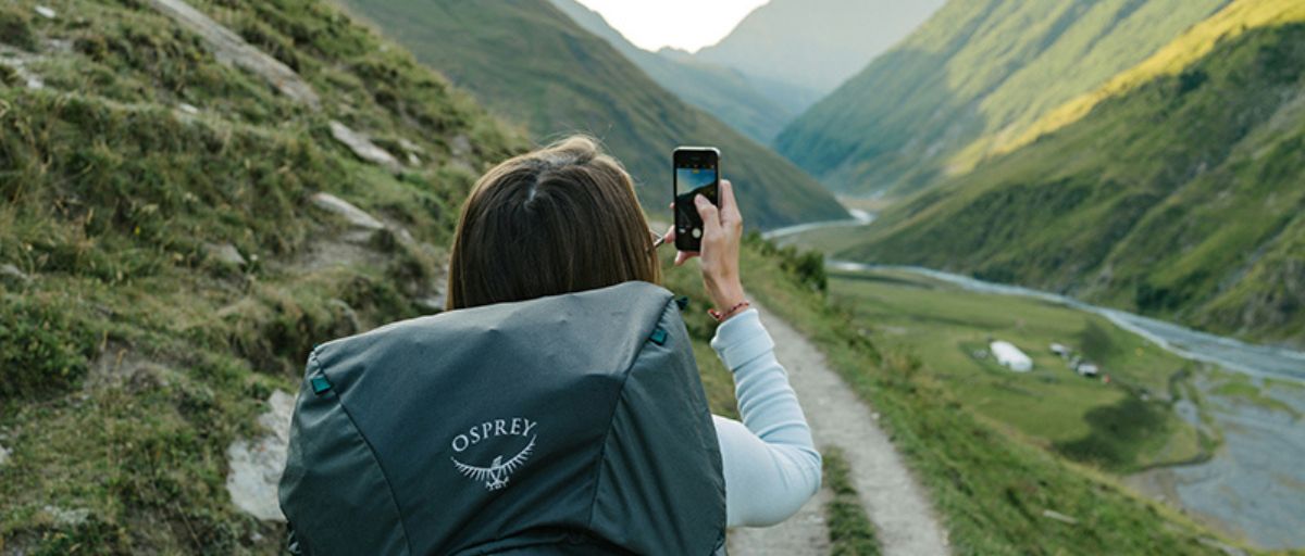 Frau mit Handy bei Hüttenwanderung, Packliste