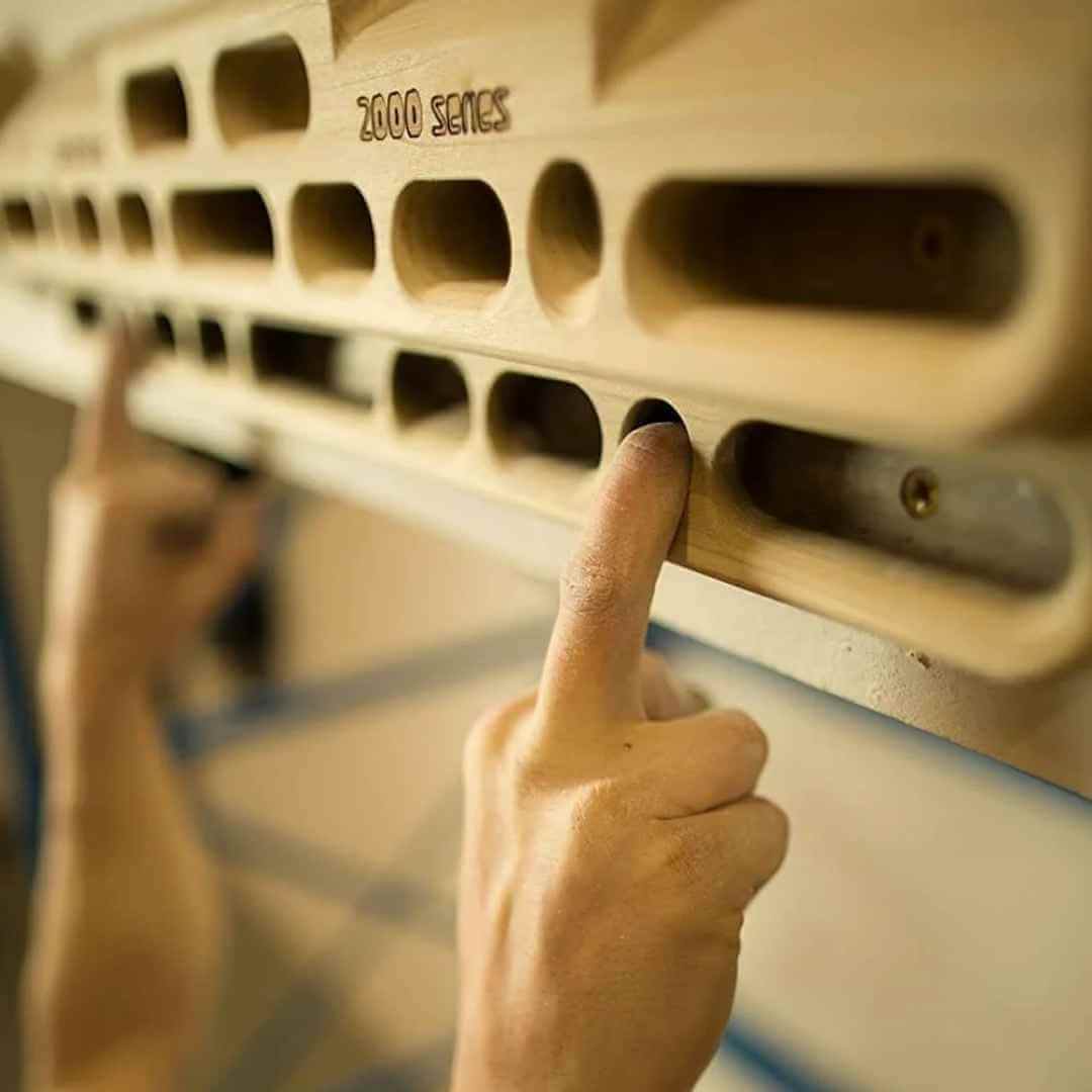 Hier ist das Trainingsboard Beastmaker 2000 Series Hangboard im Einsatz - ein Kletterer hängt mit 2 Fingern im Board